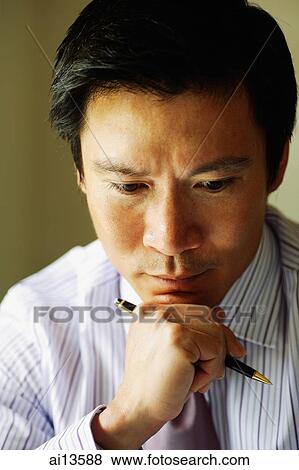Businessman holding pen, hand on chin View Large Photo Image Stock Photo - Businessman holding pen, hand on chin. Fotosearch