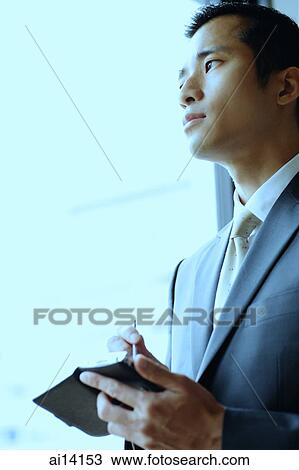 Stock Image - Businessman looking away, holding PDA. Fotosearch