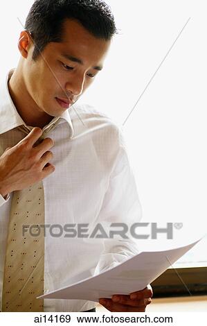 Businessman with hand on tie, holding paper View Large Photo Image Stock Photo - Businessman with hand on tie, holding paper. Fotosearch