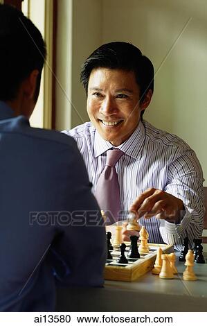 Stock Image - Businessmen playing chess, one smiling. Fotosearch