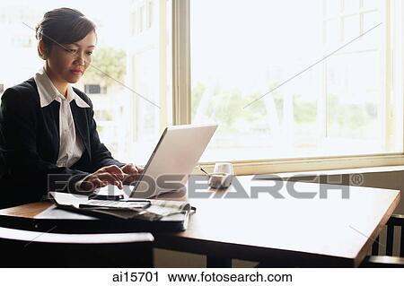 Businesswoman at table, using laptop View Large Photo Image Stock Image - Businesswoman at table, using laptop. Fotosearch
