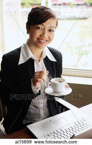 Stock Photo - Businesswoman holding cup and saucer, smiling at camera. Fotosearch