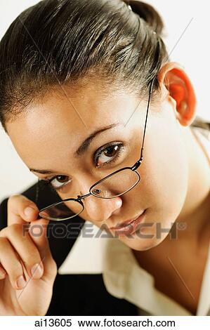 Stock Photography - Businesswoman holding glasses, looking at camera. Fotosearch