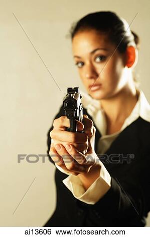 Stock Photograph - Businesswoman holding gun, looking at camera. Fotosearch