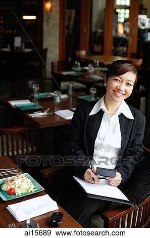 Businesswoman in restaurant, holding pen and folder, smiling View Large Photo Image Stock Photo - Businesswoman in restaurant, holding pen and folder, smiling. Fotosearch