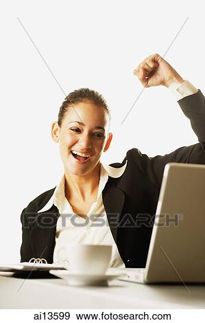 Businesswoman raising fist, looking at laptop View Large Photo Image Stock Photo - Businesswoman raising fist, looking at laptop. Fotosearch