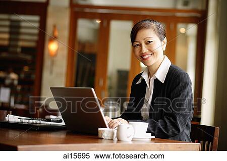 Businesswoman using laptop, smiling at camera View Large Photo Image Stock Photography - Businesswoman using laptop, smiling at camera. Fotosearch