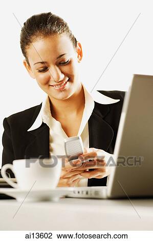 Businesswoman using mobile phone, laptop in front of her View Large Photo Image Stock Image - Businesswoman using mobile phone, laptop in front of her. Fotosearch