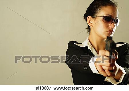 Stock Photo - Businesswoman wearing sunglasses, holding gun. Fotosearch