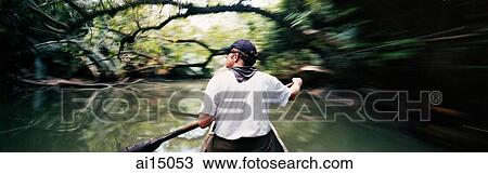 Stock Image - Caucasian male paddling dugout canoe. Fotosearch