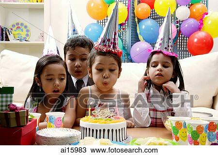 Stock Image - Children celebrating birthday, child blowing candles on cake. Fotosearch