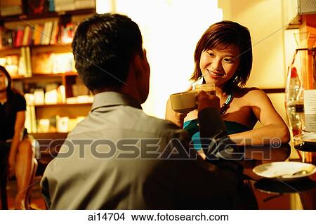 Picture - Couple at bar counter, sitting face to face, holding drinks. Fotosearch