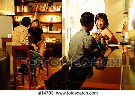 Couple at bar counter, sitting face to face, people in the background View Large Photo Image Stock Image - Couple at bar counter, sitting face to face, people in the background. Fotosearch