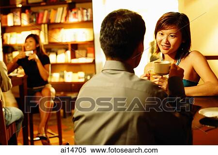 Couple at bar counter, sitting face to face, holding drinks View Large Photo Image Stock Photography - Couple at bar counter, sitting face to face, holding drinks. Fotosearch