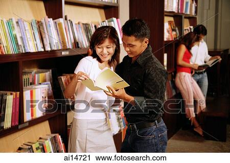 Couple at bookstore, looking at book, people in the background View Large Photo Image Stock Image - Couple at bookstore, looking at book, people in the background. Fotosearch