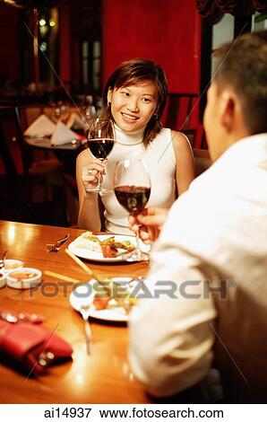 Couple at restaurant, wine glasses in hand View Large Photo Image Stock Photo - Couple at restaurant, wine glasses in hand. Fotosearch