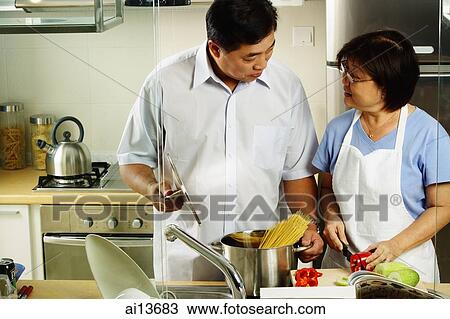 Stock Image - Couple cooking in kitchen. Fotosearch