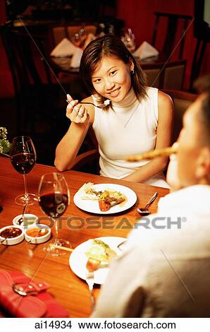 Couple eating at restaurant, over the shoulder view View Large Photo Image Picture - Couple eating at restaurant, over the shoulder view. Fotosearch