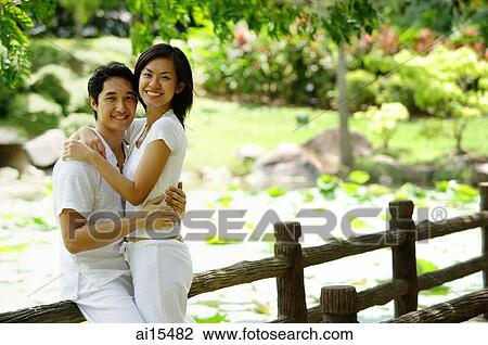 Stock Image - Couple embracing, smiling at camera, portrait. Fotosearch