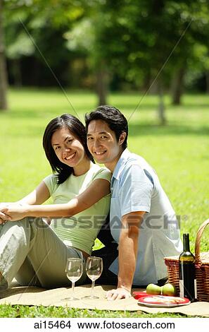 Couple having picnic in park, looking at camera View Large Photo Image Picture - Couple having picnic in park, looking at camera. Fotosearch