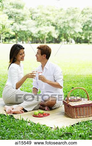 Couple having picnic in park, toasting with drinks View Large Photo Image Stock Photo - Couple having picnic in park, toasting with drinks. Fotosearch
