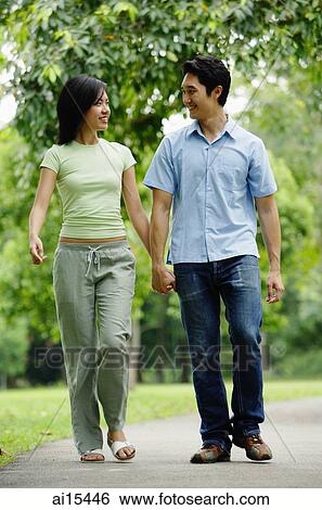 Stock Photograph - Couple holding hands and walking in park. Fotosearch