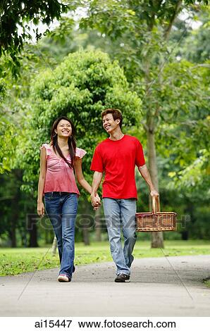 Couple holding hands and walking in park, man carrying picnic basket View Large Photo Image Stock Photo - Couple holding hands and walking in park, man carrying picnic basket. Fotosearch