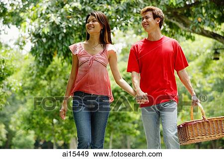 Stock Photo - Couple holding hands, man carrying picnic basket. Fotosearch