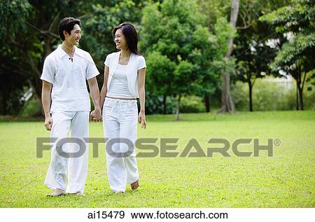 Stock Photo - Couple holding hands, walking across field. Fotosearch