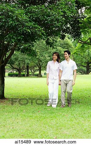 Stock Photo - Couple holding hands, walking across park. Fotosearch