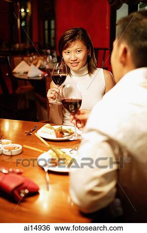 Couple holding wine glasses at restaurant View Large Photo Image Stock Photograph - Couple holding wine glasses at restaurant. Fotosearch