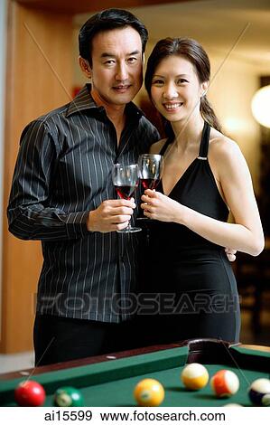 Couple holding wine glasses, standing side by side, smiling at camera View Large Photo Image Stock Photo - Couple holding wine glasses, standing side by side, smiling at camera. Fotosearch