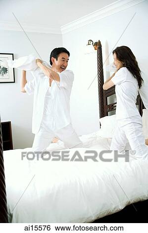 Stock Photograph - Couple in bedroom, having pillow fight. Fotosearch