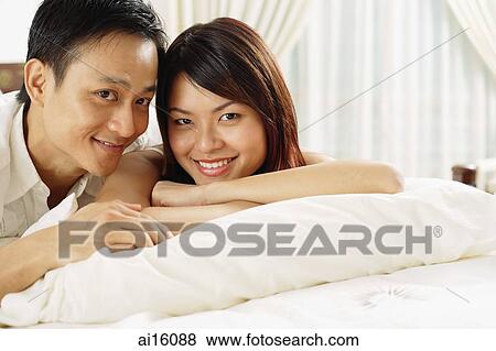 Couple in bedroom, lying on bed, looking at camera View Large Photo Image Stock Photo - Couple in bedroom, lying on bed, looking at camera. Fotosearch