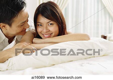 Couple in bedroom, lying on bed, woman looking at camera View Large Photo Image Stock Photo - Couple in bedroom, lying on bed, woman looking at camera. Fotosearch