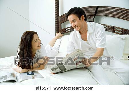 Couple in bedroom, man showing woman newspaper View Large Photo Image Stock Image - Couple in bedroom, man showing woman newspaper. Fotosearch