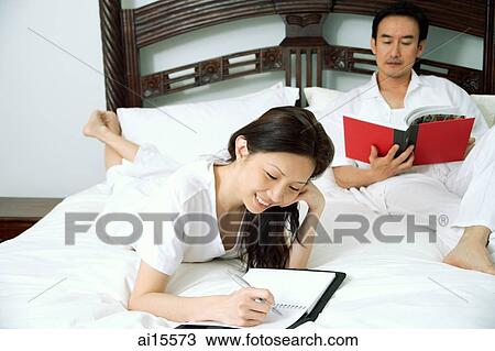 Couple in bedroom, woman writing in diary, man reading book View Large Photo Image Stock Image - Couple in bedroom, woman writing in diary, man reading book. Fotosearch
