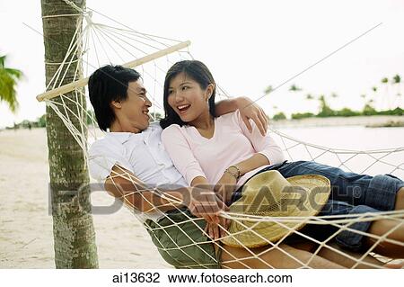 Stock Image - Couple in hammock, looking at each other. Fotosearch