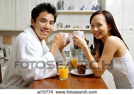 Couple in kitchen, having breakfast, smiling at camera View Large Photo Image Picture - Couple in kitchen, having breakfast, smiling at camera. Fotosearch