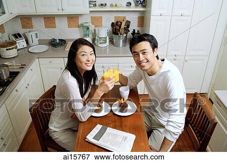 Couple in kitchen, having breakfast, smiling at camera View Large Photo Image Stock Photo - Couple in kitchen, having breakfast, smiling at camera. Fotosearch