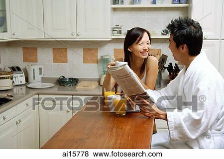 Couple in kitchen, having breakfast, man holding newspaper View Large Photo Image Stock Photo - Couple in kitchen, having breakfast, man holding newspaper. Fotosearch