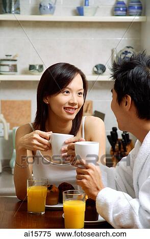 Couple in kitchen, having breakfast, both holding mugs View Large Photo Image Stock Photography - Couple in kitchen, having breakfast, both holding mugs. Fotosearch