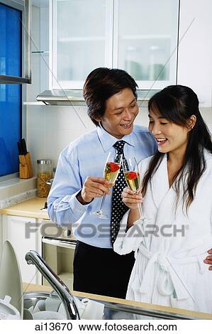 Couple in kitchen holding champagne View Large Photo Image Stock Image - Couple in kitchen holding champagne. Fotosearch