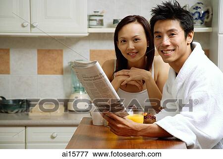 Couple in kitchen, man holding newspaper, smiling at camera View Large Photo Image Stock Photo - Couple in kitchen, man holding newspaper, smiling at camera. Fotosearch