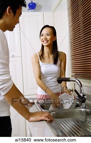 Couple in kitchen, man washing dishes, smiling at woman View Large Photo Image Stock Image - Couple in kitchen, man washing dishes, smiling at woman. Fotosearch