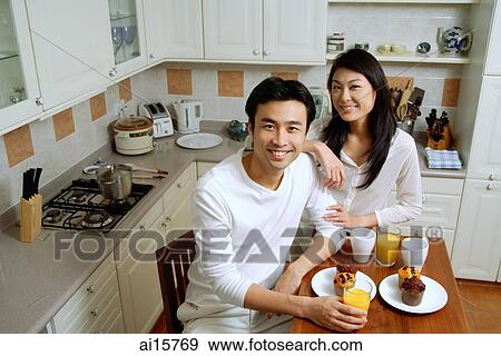 Stock Photo - Couple in kitchen, smiling at camera. Fotosearch
