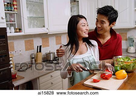 Couple in kitchen, smiling at each other, woman chopping vegetables View Large Photo Image Stock Photo - Couple in kitchen, smiling at each other, woman chopping vegetables. Fotosearch