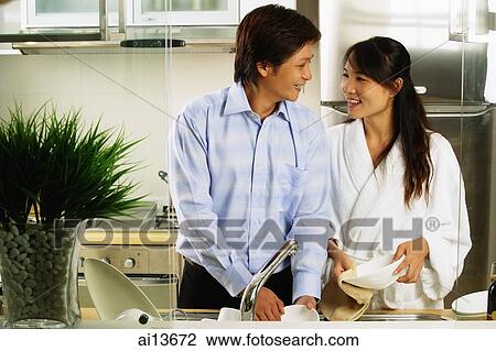 Stock Image - Couple in kitchen washing dishes. Fotosearch