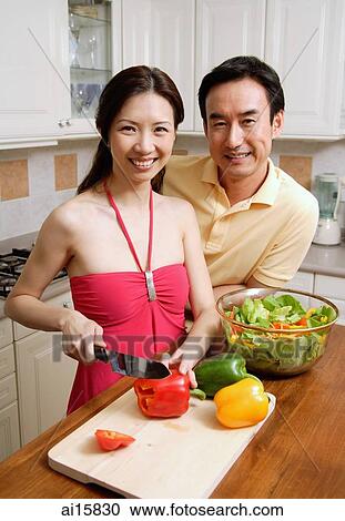 Couple in kitchen, woman chopping vegetables, smiling at camera View Large Photo Image Stock Image - Couple in kitchen, woman chopping vegetables, smiling at camera. Fotosearch