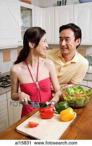 Couple in kitchen, woman chopping vegetables, looking over shoulder, smiling at man View Large Photo Image Stock Image - Couple in kitchen, woman chopping vegetables, looking over shoulder, smiling at man. Fotosearch